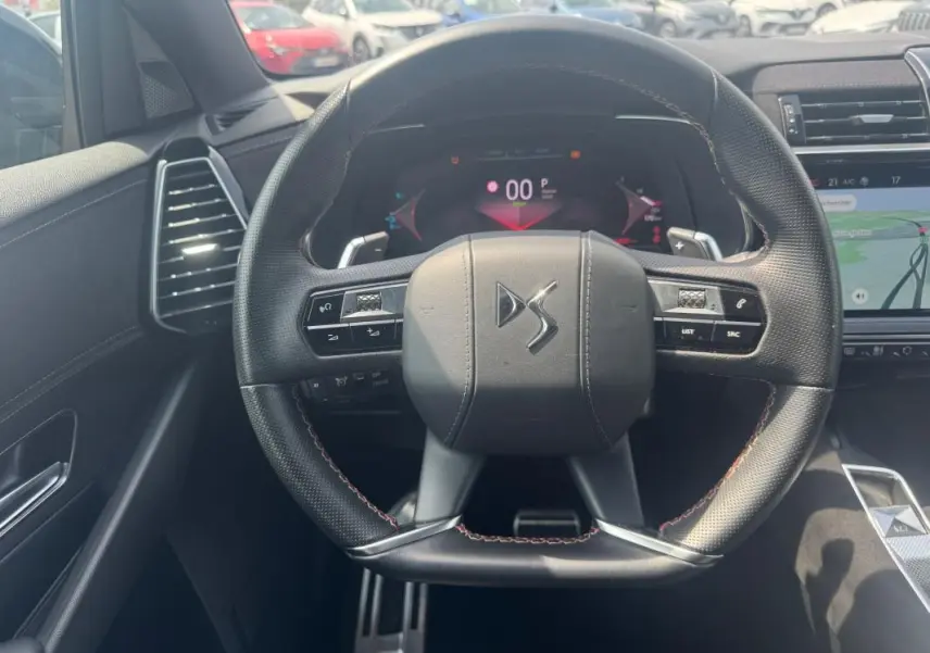 Vue intérieure centrée sur le volant noir perforé du DS7 E-Tense 2024 avec tableau de bord numérique et écran tactile.