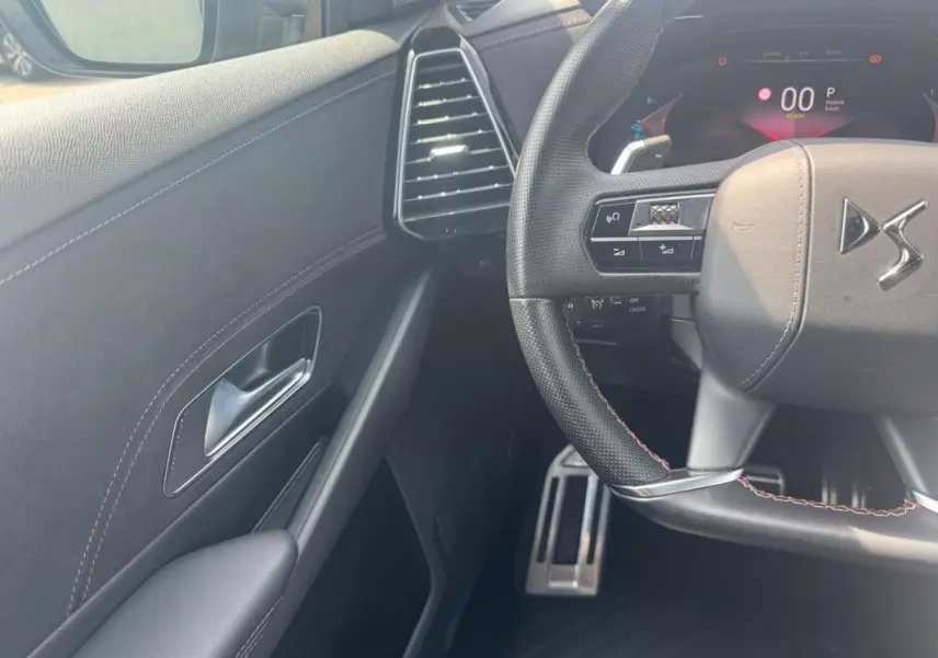 Vue intérieure côté gauche du volant du DS7 gris foncé, avec volant multifonction et tableau de bord numérique.