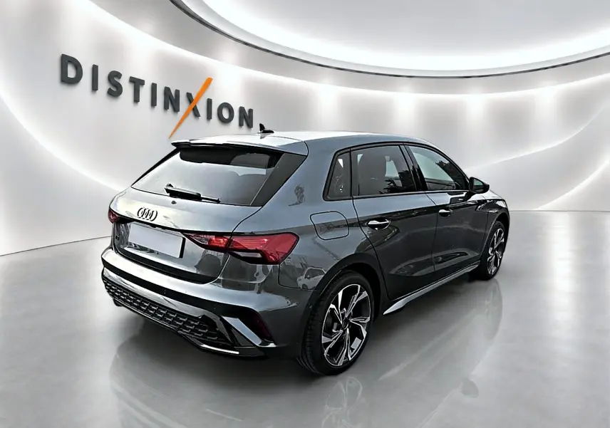 Audi A3 Sportback gris Daytona vue 3/4 arrière droit dans un showroom lumineux avec jantes alu graphiques.