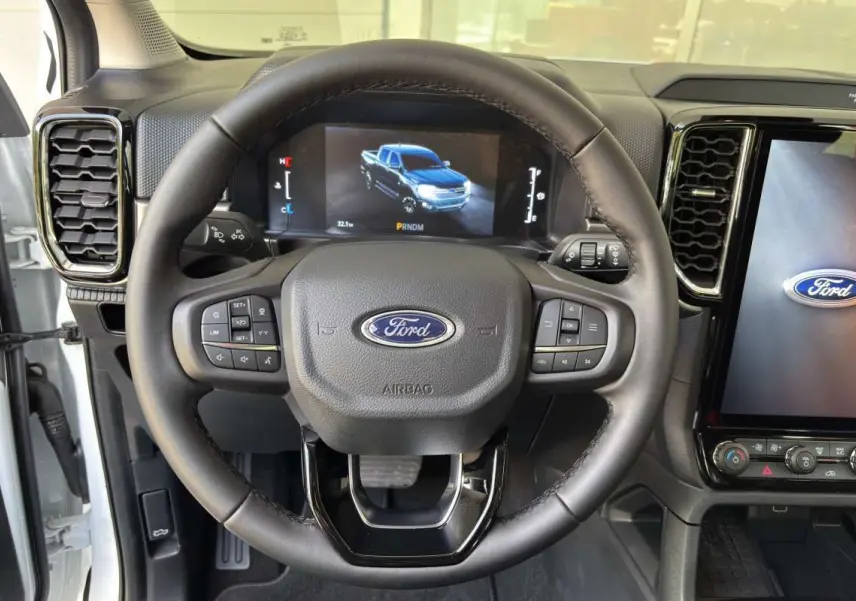 Vue centrée sur le volant du Ford Ranger blanc glacier 2026 avec tableau de bord numérique et écran tactile.