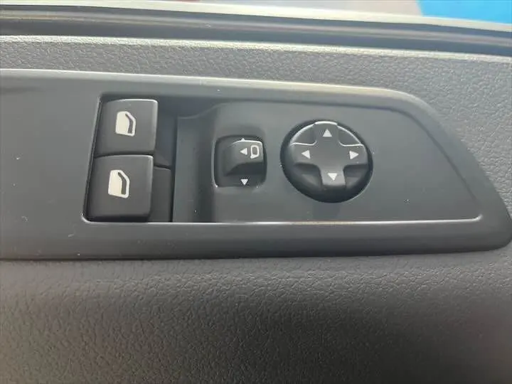 Panneau de commandes des rétroviseurs et des vitres électriques sur la portière intérieure d'un Fiat Scudo Fourgon blanc.