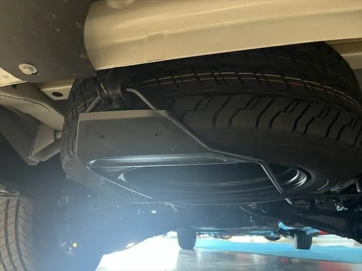Gros plan sous le FIAT Scudo Fourgon blanc montrant la roue de secours fixée sous le châssis arrière.