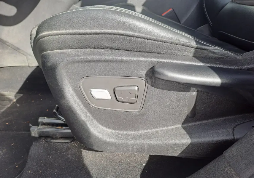 Gros plan sur les commandes de réglage électrique du siège conducteur en cuir noir du Renault Scenic IV gris platine.