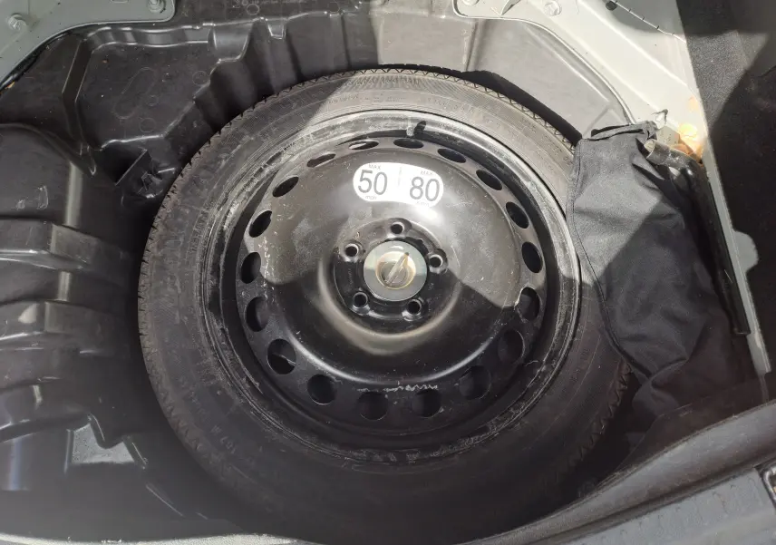 Gros plan sur la roue de secours noire dans le coffre d’un Renault Scenic IV gris platine, version essence 2018.