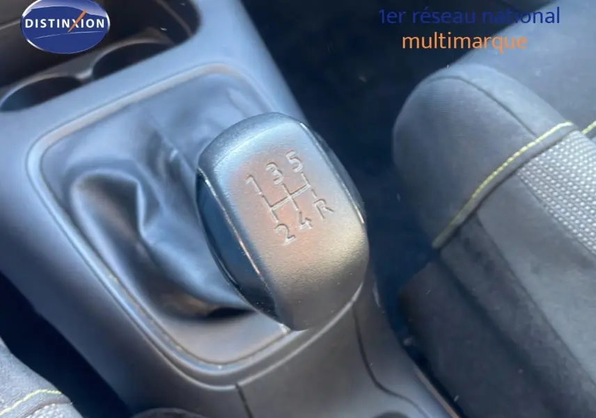 Gros plan sur le levier de vitesses manuel noir et tissu de siège gris avec surpiqûres jaunes dans une Citroën C3 blanche.