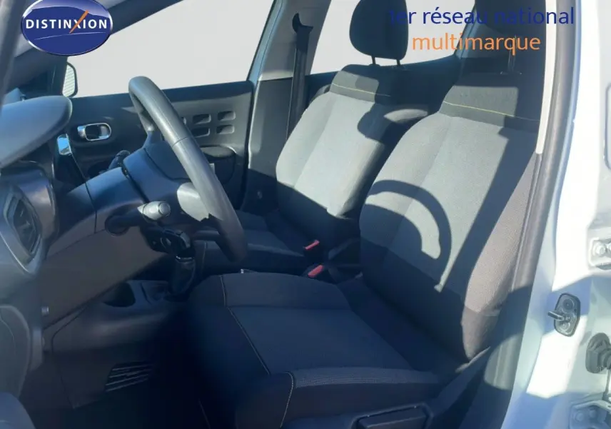 Intérieur côté conducteur d'une Citroën C3 blanche banquise 2020, sièges tissu gris et volant multifonction.