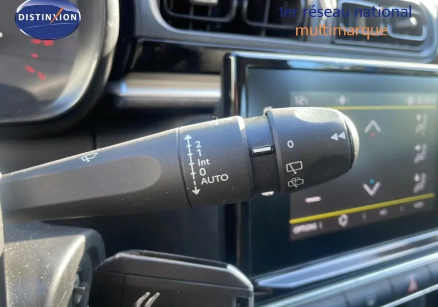 Gros plan sur la commande d'essuie-glace à gauche du volant dans l'habitacle d'une Citroën C3 blanc banquise.