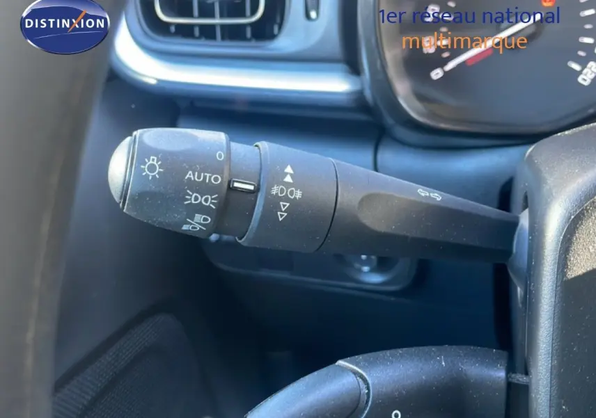 Gros plan sur la commande des phares et clignotants dans l'habitacle noir d'une Citroën C3 blanche banquise 2020.