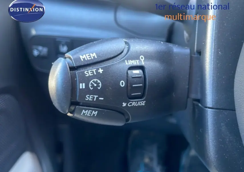 Gros plan sur la commande de régulateur de vitesse noire dans l'habitacle d'une Citroën C3 blanc banquise.