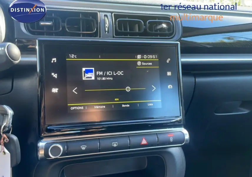 Vue rapprochée de la console centrale de la Citroën C3 blanche, avec écran tactile affichant une radio FM.