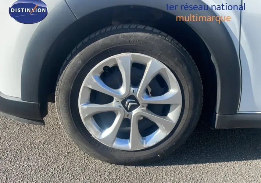Gros plan sur la roue avant droite d'une Citroën C3 blanc banquise avec jante en alliage distinctive.