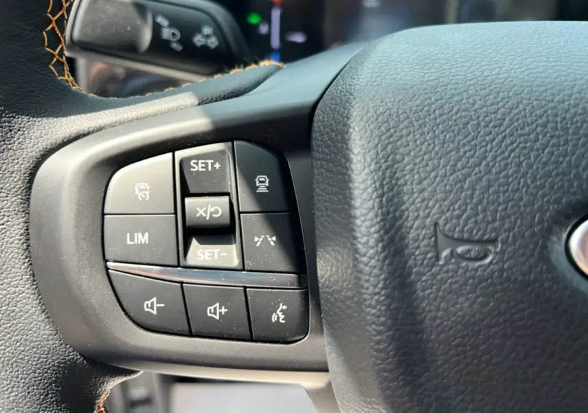 Gros plan sur les commandes multifonctions du volant en cuir noir du Ford Ranger Wildtrak Plus 2025.