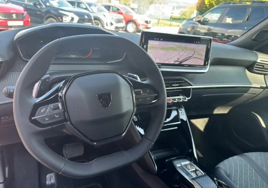 Vue intérieure centrée sur le volant cuir multifonctions et l'écran tactile 10 pouces du Peugeot 2008 Hybrid rouge Elixir.