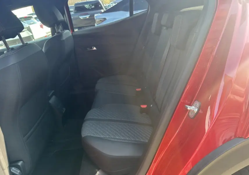 Vue côté arrière droit de l’habitacle d’un Peugeot 2008 rouge elixir, montrant la banquette arrière en tissu noir.