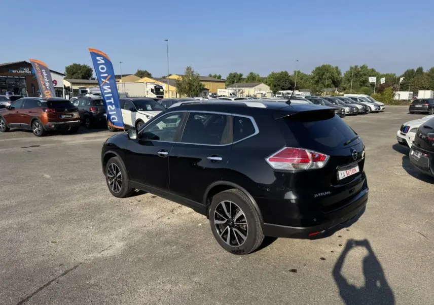 Nissan X-Trail noir vue 3/4 arrière droit sur parking, jantes alliage et vitres teintées visibles.