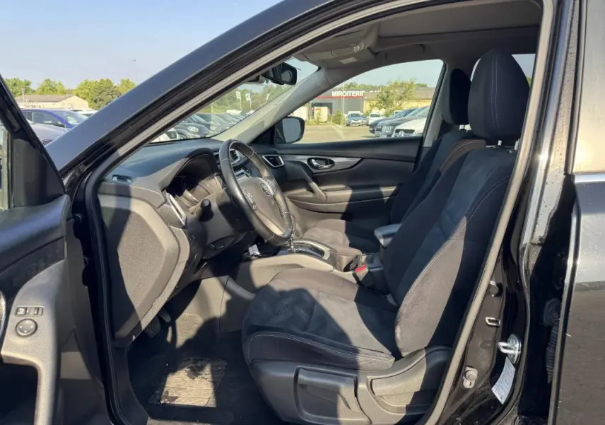 Intérieur avant droit du Nissan X-TRAIL III noir 2017, montrant les sièges tissu et le tableau de bord avec volant.