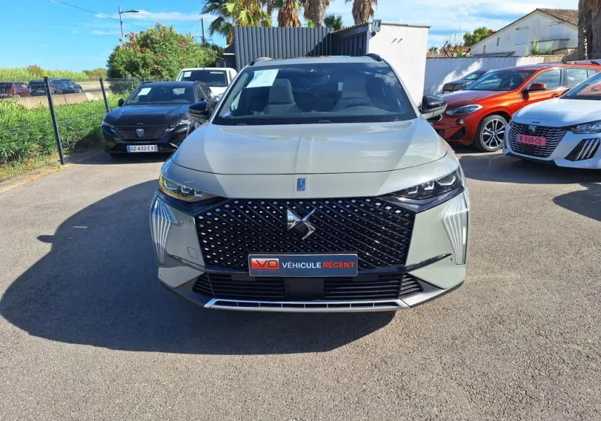 Vue avant d'un DS7 gris 2024 avec calandre distinctive et feux LED, stationné en extérieur sur un parking.