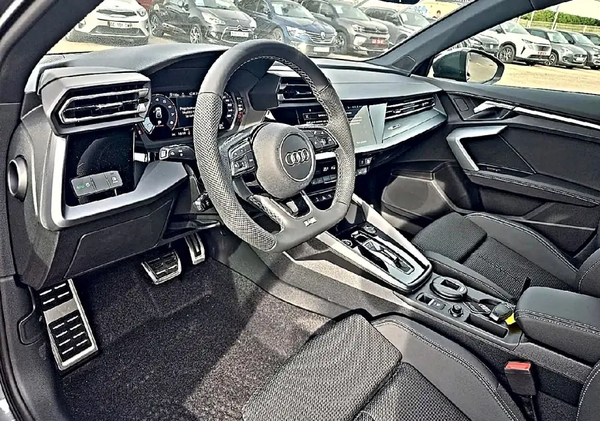 Vue intérieure côté conducteur de l'Audi A3 Sportback 2026, volant sport et console centrale moderne en noir.