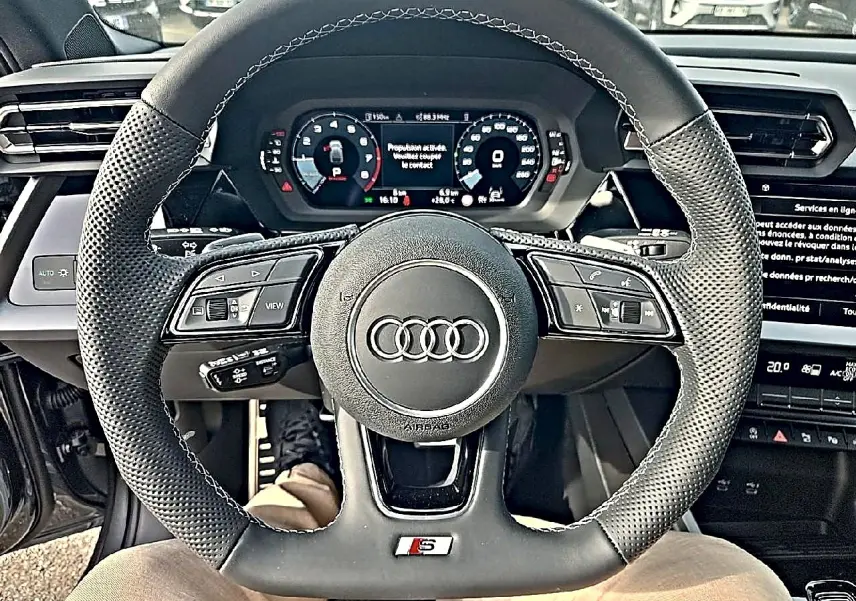 Vue rapprochée du volant sport en cuir noir avec logo Audi et tableau de bord numérique de l'Audi A3 Sportback.
