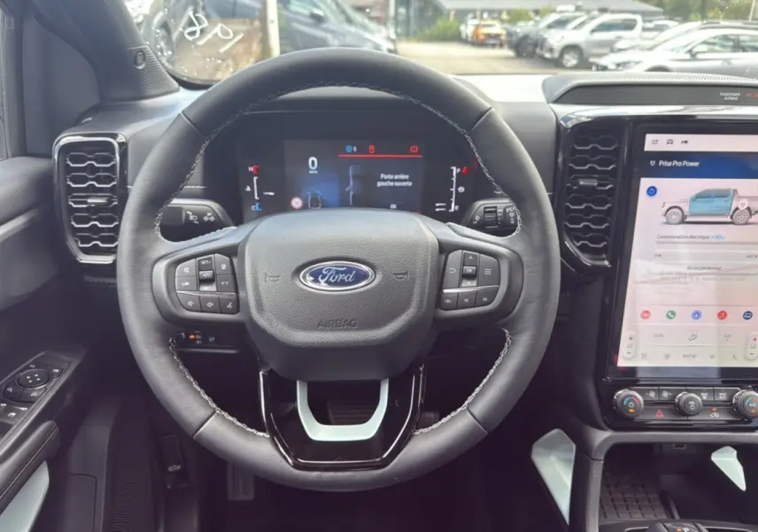 Vue intérieure centrée sur le volant cuir multifonctions d’un Ford Ranger 2.3 PHEV avec écran tactile et commandes au volant.