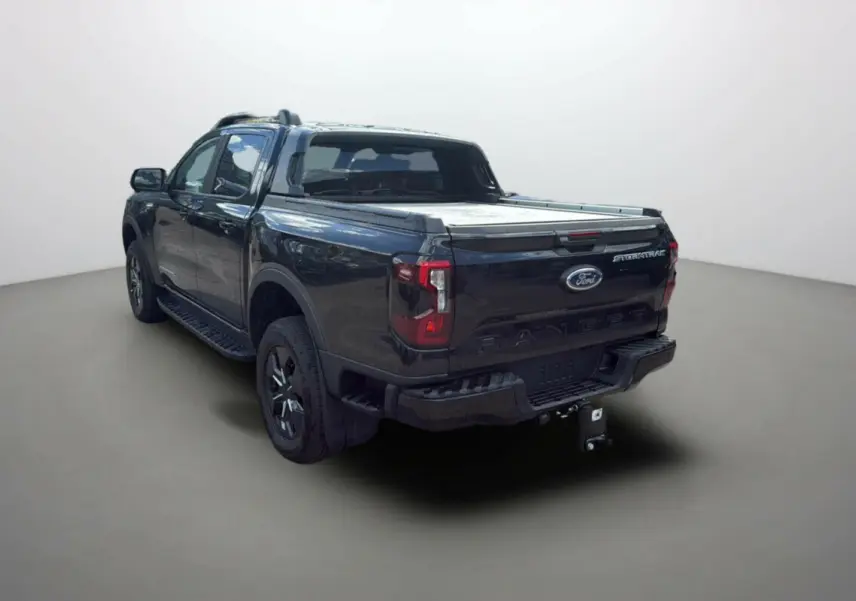 Ford Ranger 2.3 PHEV noir agate vu 3/4 arrière droit avec arceau sport et attelage visible.