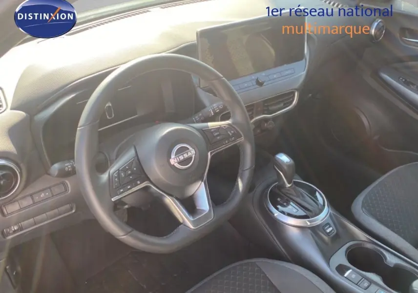 Vue intérieure centrée sur le volant Nissan et la console centrale du Juke 1.6 Full Hybrid avec sellerie noire.