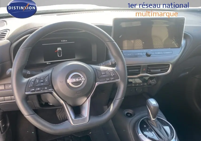 Vue intérieure du tableau de bord du Nissan Juke 2025, volant cuir noir et écran tactile central.