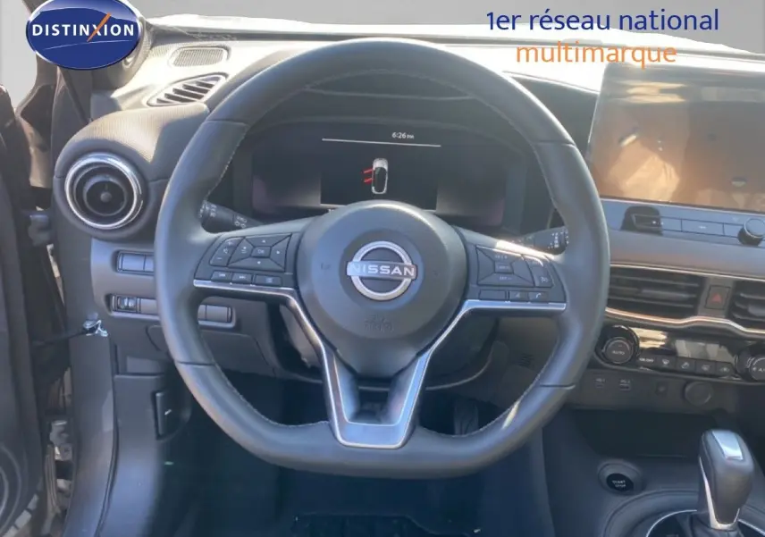 Vue intérieure centrée sur le volant Nissan du Juke 2025, avec tableau de bord et console en arrière-plan.
