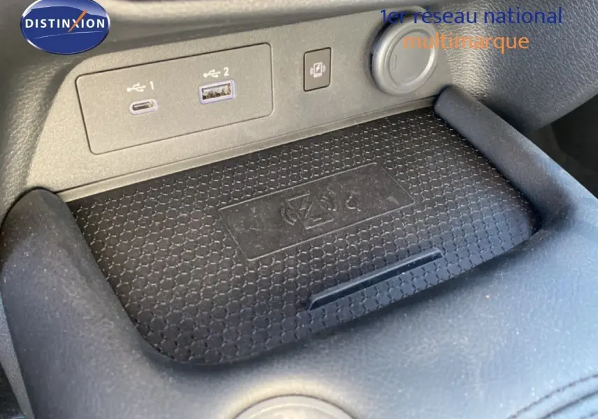 Gros plan sur la console centrale du Nissan Juke 2025, montrant les ports USB et la zone de charge sans fil.