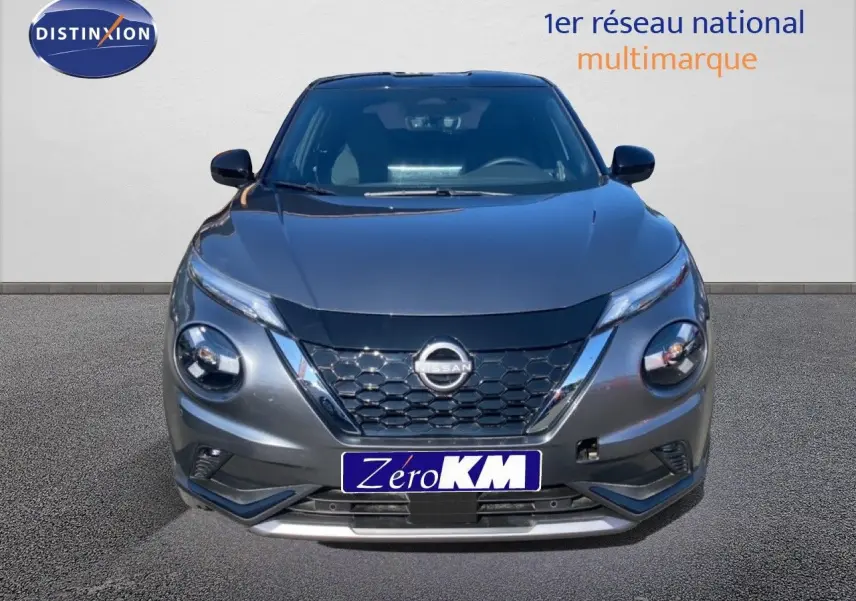 Vue avant d'un Nissan Juke 1.6 Full Hybrid gris squale métal avec toit noir, mettant en valeur sa calandre hexagonale distinctive.