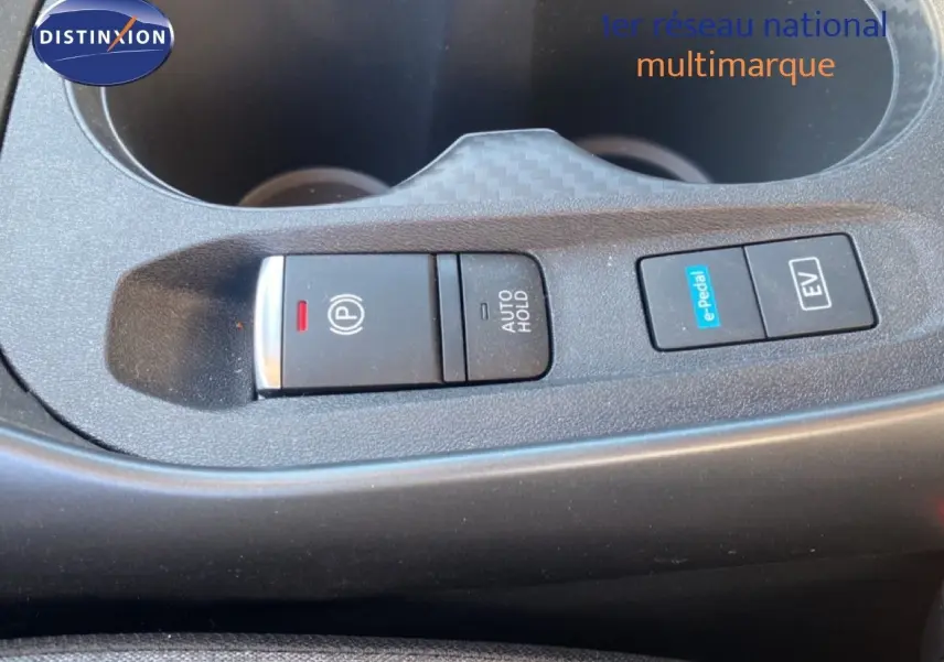Gros plan sur la console centrale du Nissan Juke 2025, boutons de frein à main électrique et modes e-Pedal et EV visibles.