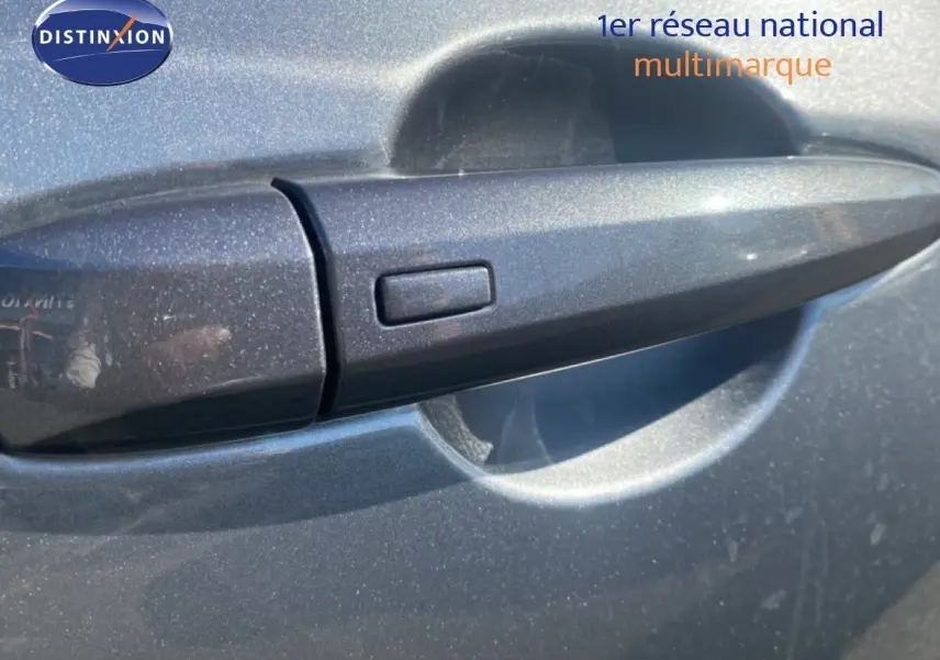 Poignée de porte avant gauche gris squale métal du Nissan Juke 2025 avec bouton de déverrouillage intégré.