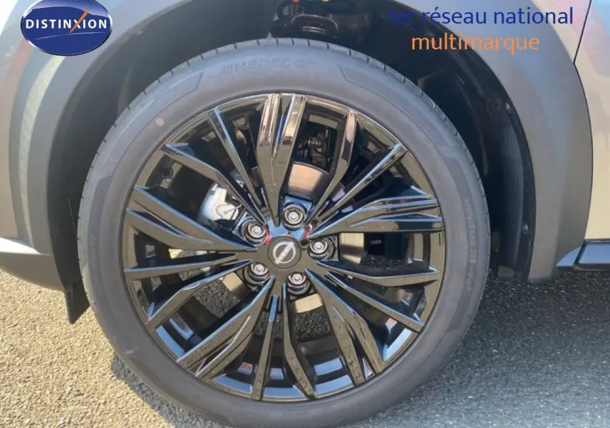 Gros plan sur la roue avant droite du Nissan Juke 2025, jante noire brillante avec carrosserie gris squale métal visible.