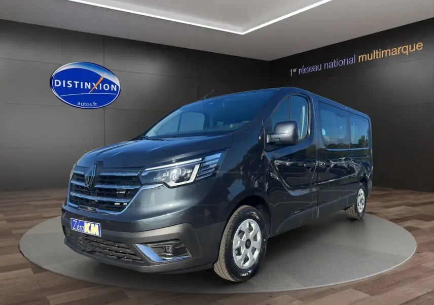 Renault Trafic Combi gris comète en vue 3/4 avant droit, avec portes latérales vitrées et jantes tôlées 16 pouces.