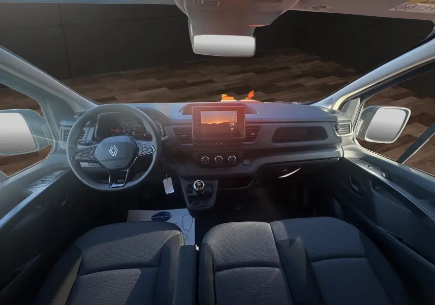 Intérieur avant du Renault Trafic Combi 2025 avec tableau de bord noir, volant multifonction et écran tactile central.