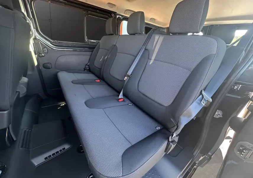 Banquette arrière en tissu noir vue côté droit dans un Renault Trafic Combi gris Comète 2025 avec porte coulissante ouverte.