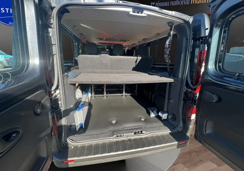 Vue arrière ouverte du Renault Trafic Combi gris comète, montrant l'espace de chargement et les sièges arrière.