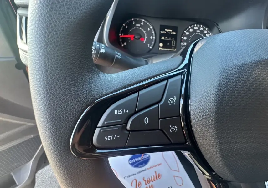 Gros plan sur les commandes du régulateur de vitesse au volant d'un Renault Trafic Combi 2025, intérieur noir.