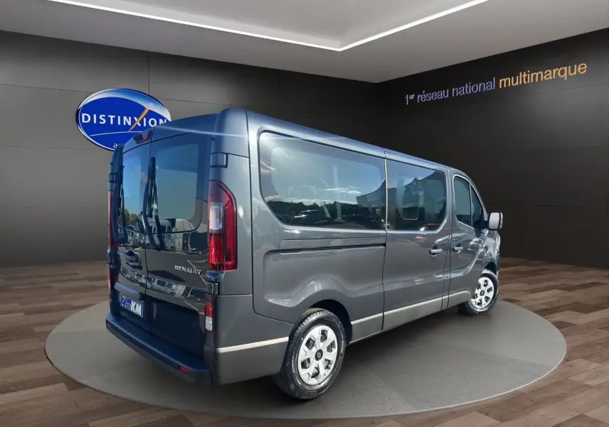 Renault Trafic Combi gris comète vu en 3/4 arrière droit, porte latérale coulissante et vitres teintées visibles.