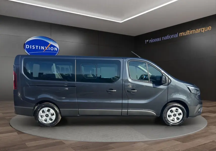 Profil côté droit du Renault Trafic Combi gris comète 2025 avec portes coulissantes vitrées et roues tôlées 16 pouces.