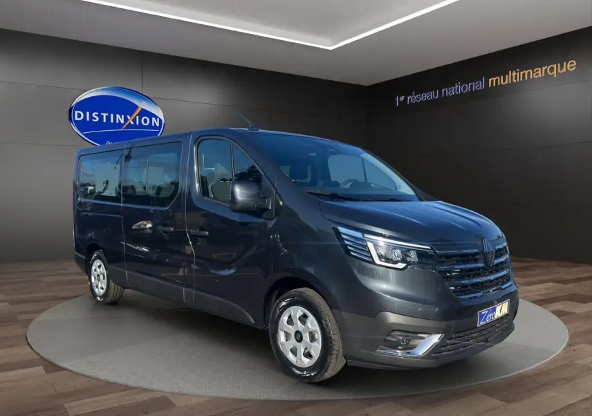 Renault Trafic Combi gris comète vu en 3/4 avant droit, avec portes latérales vitrées et jantes tôlées 16 pouces.