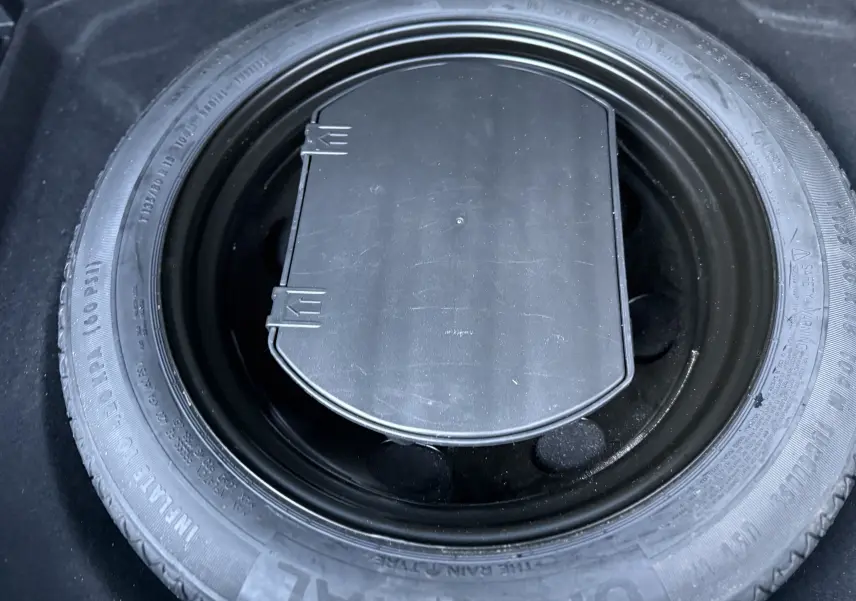 Gros plan sur la roue de secours noire logée dans le coffre du Citroën C5 Aircross blanc nacré 2021.