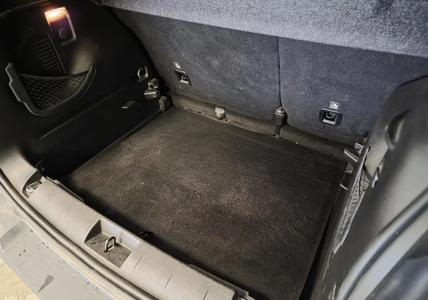 Coffre ouvert du Jeep Renegade blanc, vue plongeante montrant tapis de coffre noir et crochets d'arrimage.