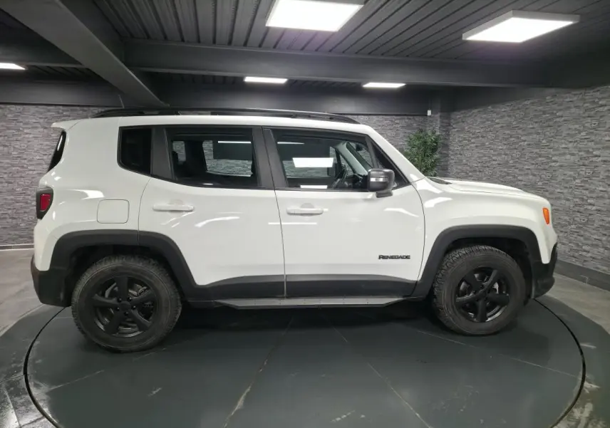 Jeep Renegade blanc vue de profil côté gauche avec jantes noires 5 branches dans un showroom.