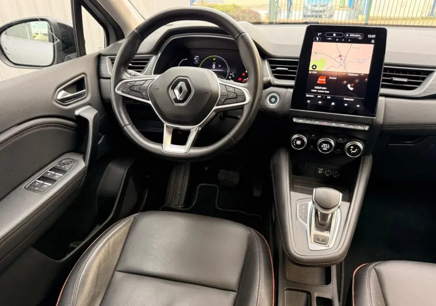 Vue intérieure du poste de conduite du Renault Captur gris Highland 2021, avec volant cuir, écran tactile et levier de boîte auto.