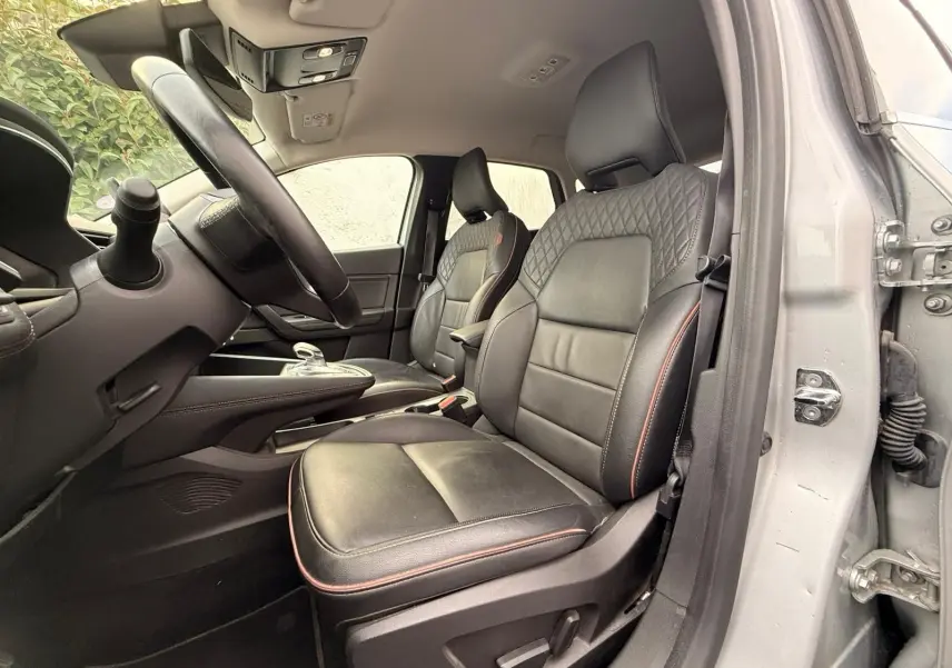 Intérieur de la Renault Captur gris Highland, vue côté conducteur sur les sièges en cuir noir avec surpiqûres rouges.