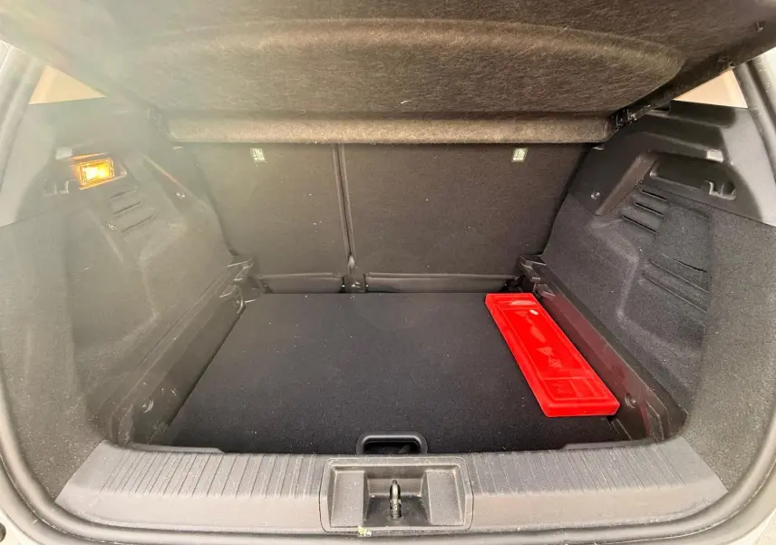 Coffre ouvert du Renault Captur gris Highland, vue intérieure arrière avec un triangle de signalisation rouge posé à droite.