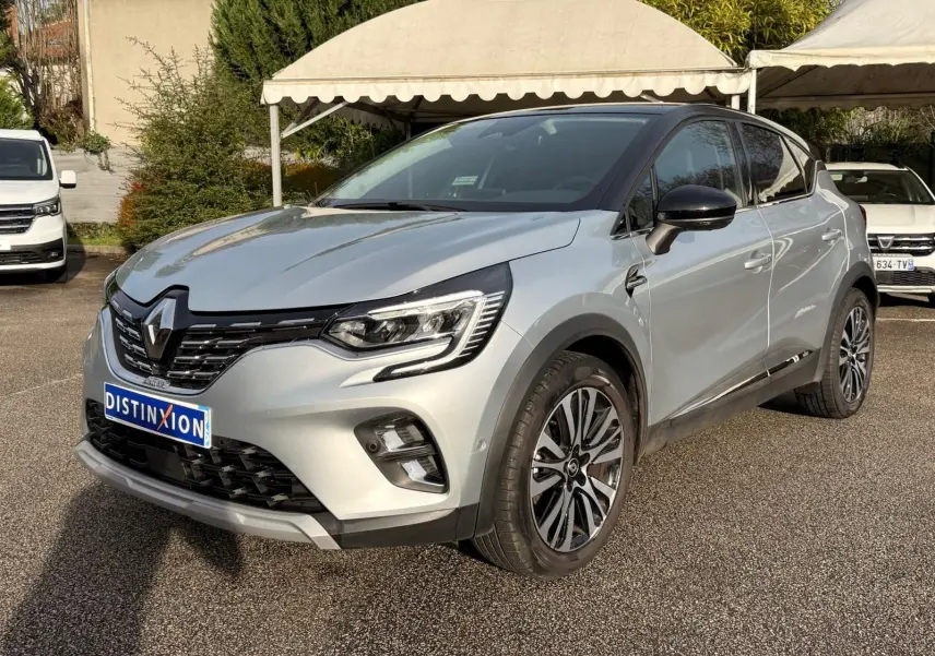 Renault Captur gris Highland en 3/4 avant droit, avec jantes alliage et toit noir contrasté visible en extérieur.
