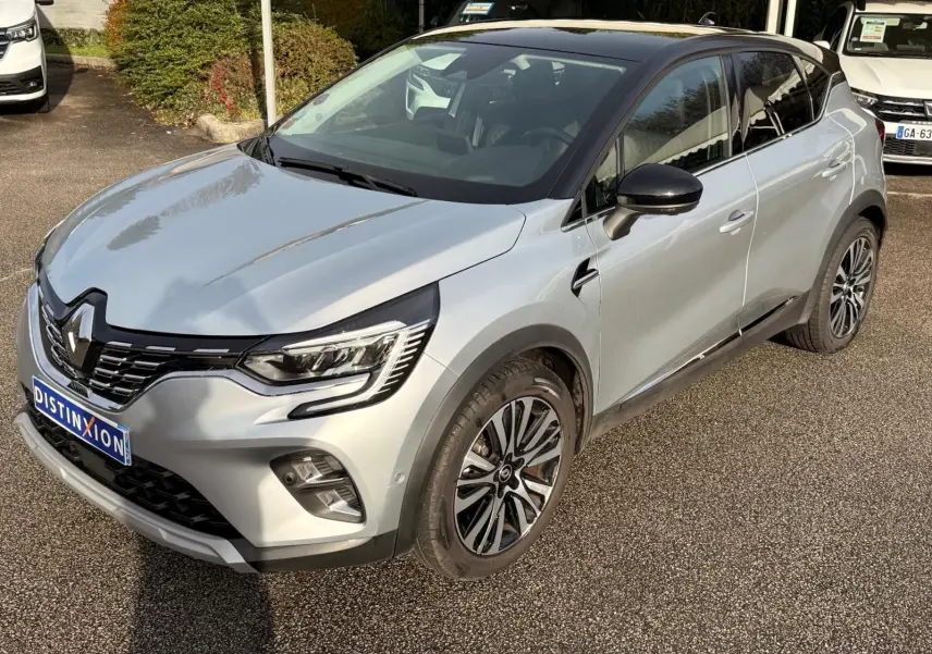Renault Captur gris Highland en 3/4 avant droit, toit noir contrasté et jantes alliage distinctives.