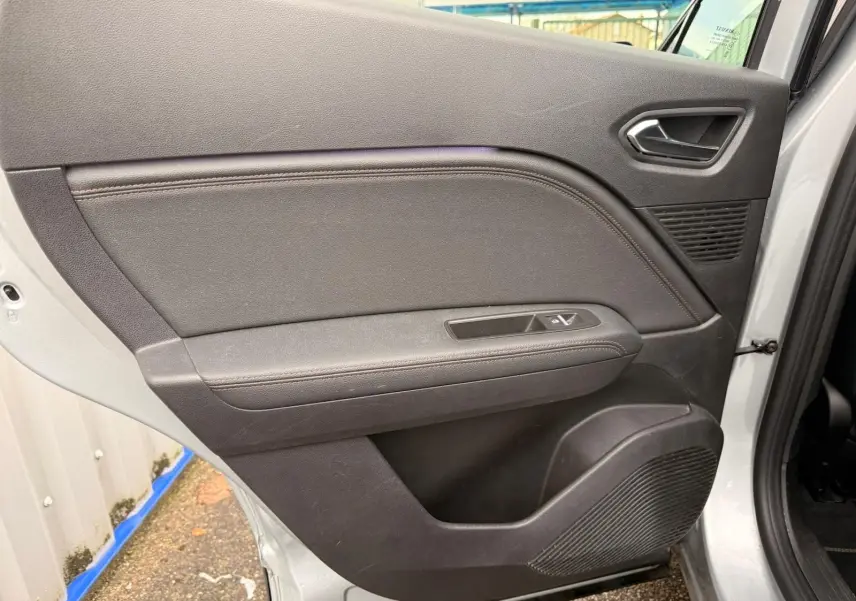 Vue intérieure de la porte arrière droite du Renault Captur gris Highland, avec commandes de fenêtre et haut-parleur intégré.